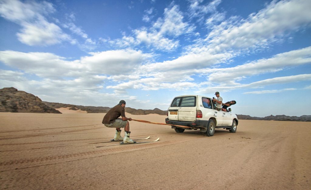 Wüstenskifahren mit einem an einem Auto befestigten Kabel.