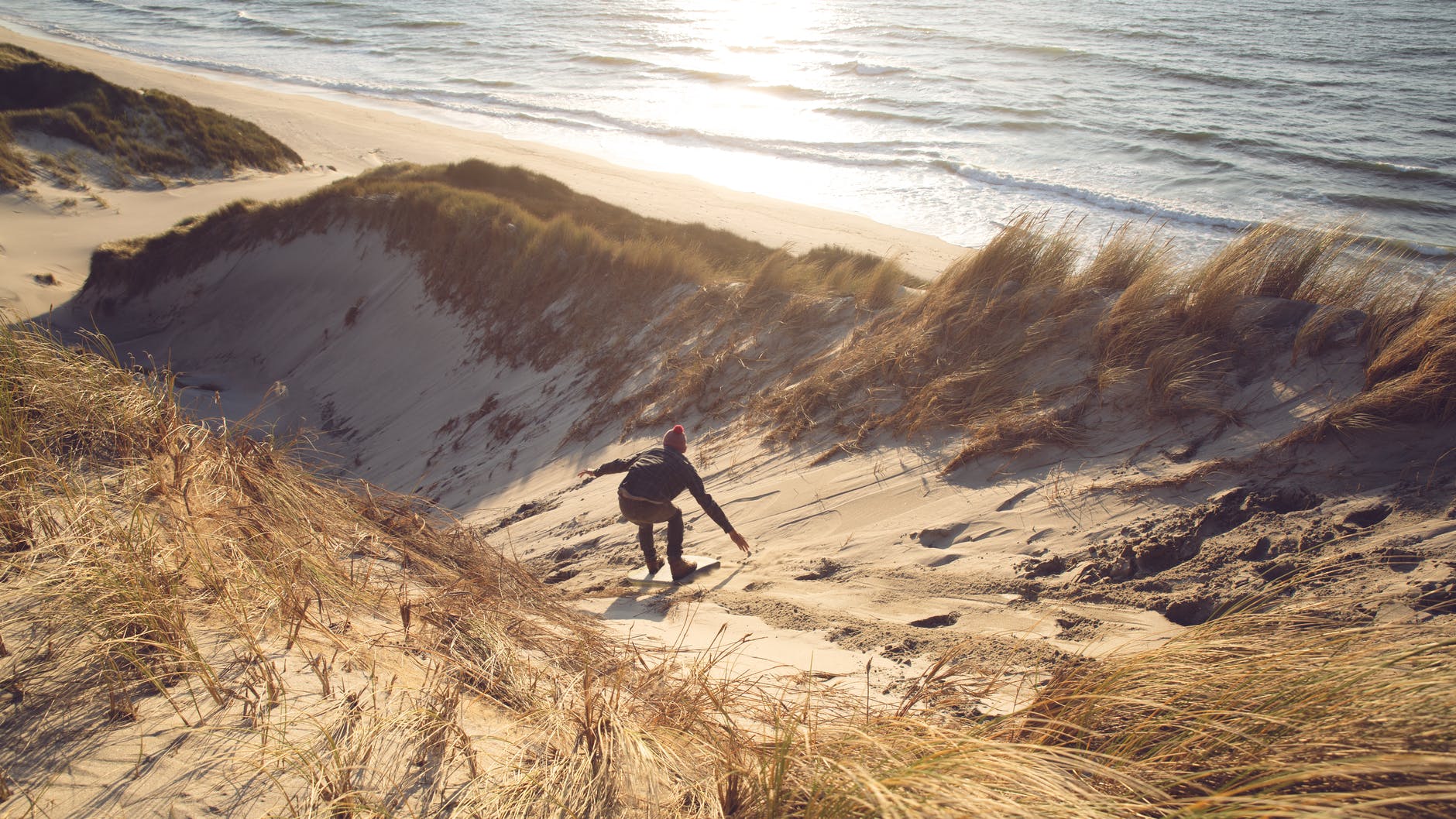 a man sandboarding over the sand hill