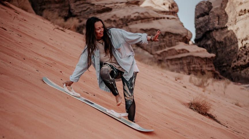 Girl sandboarding / sandsurfing in the desert