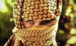 Woman wearing a shemagh desert scarf around her head and face.