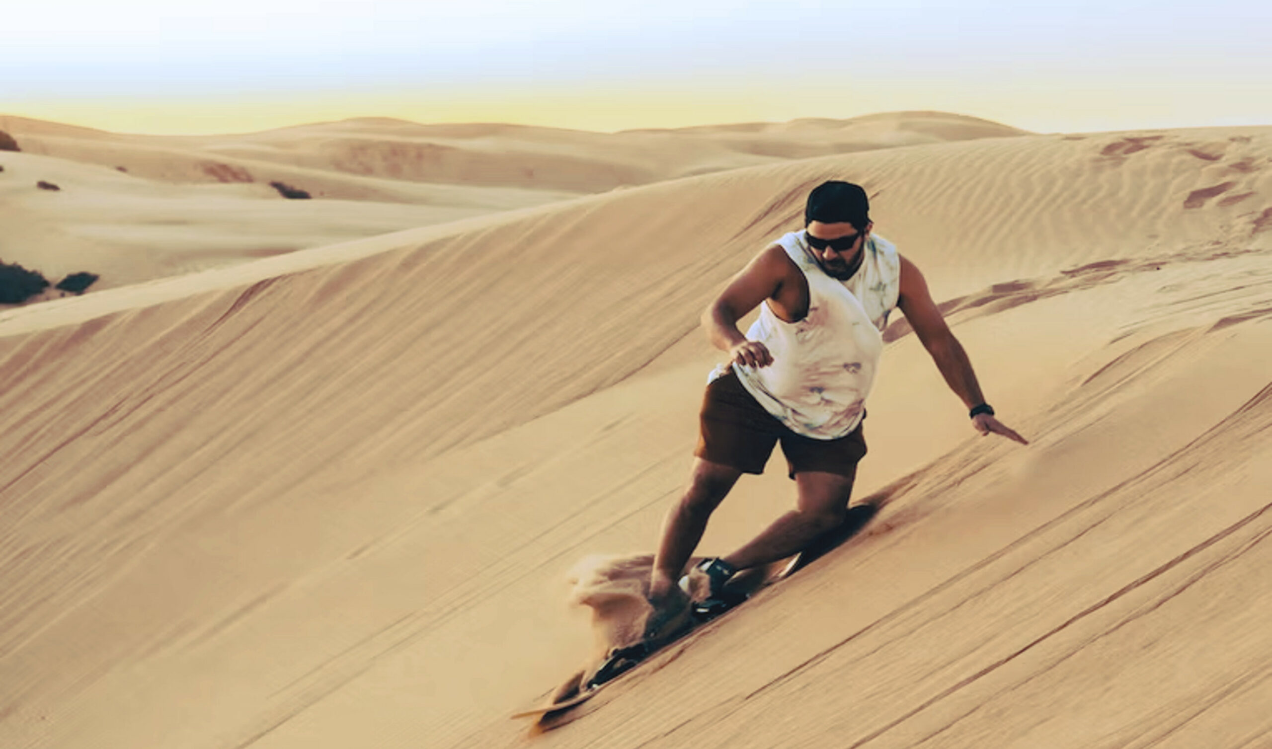 Man sandboarding on a dune in California, USA