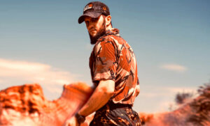 Man wearing a camo shirt and trousers in a rocky desert
