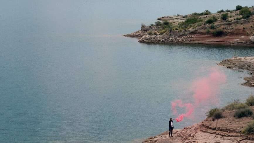 unrecognizable person in pink flare smoke on amazing seaside