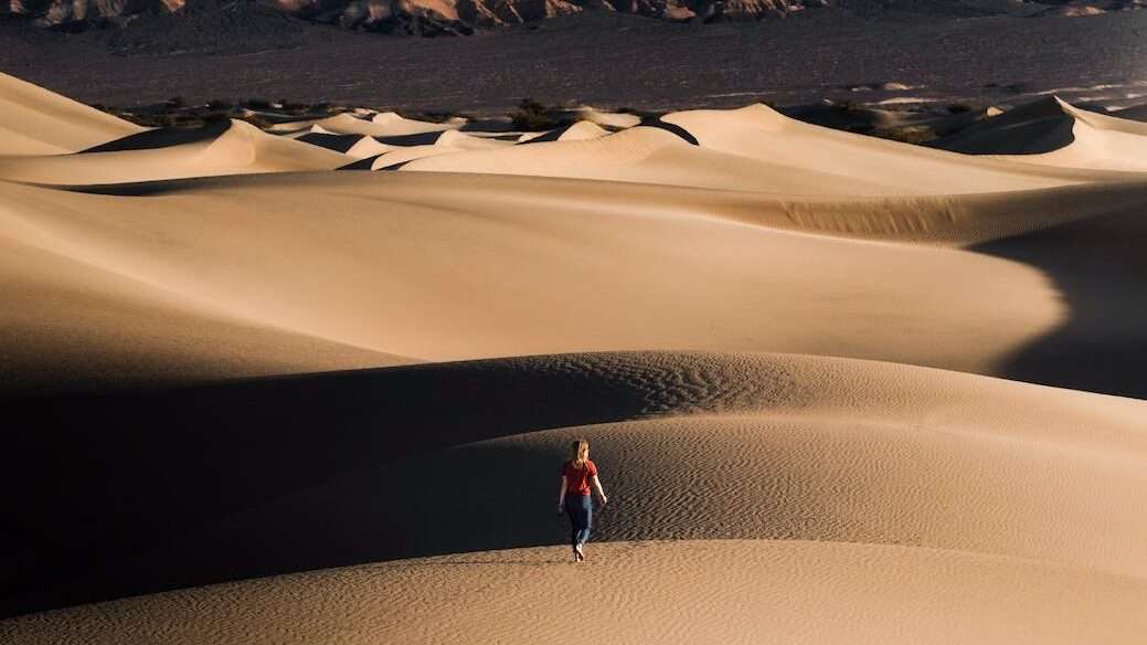 photo of a woman walking on desert