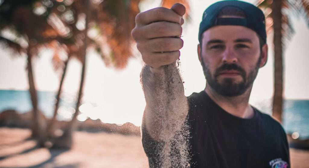 Man holding a handful of sand from the beach.
